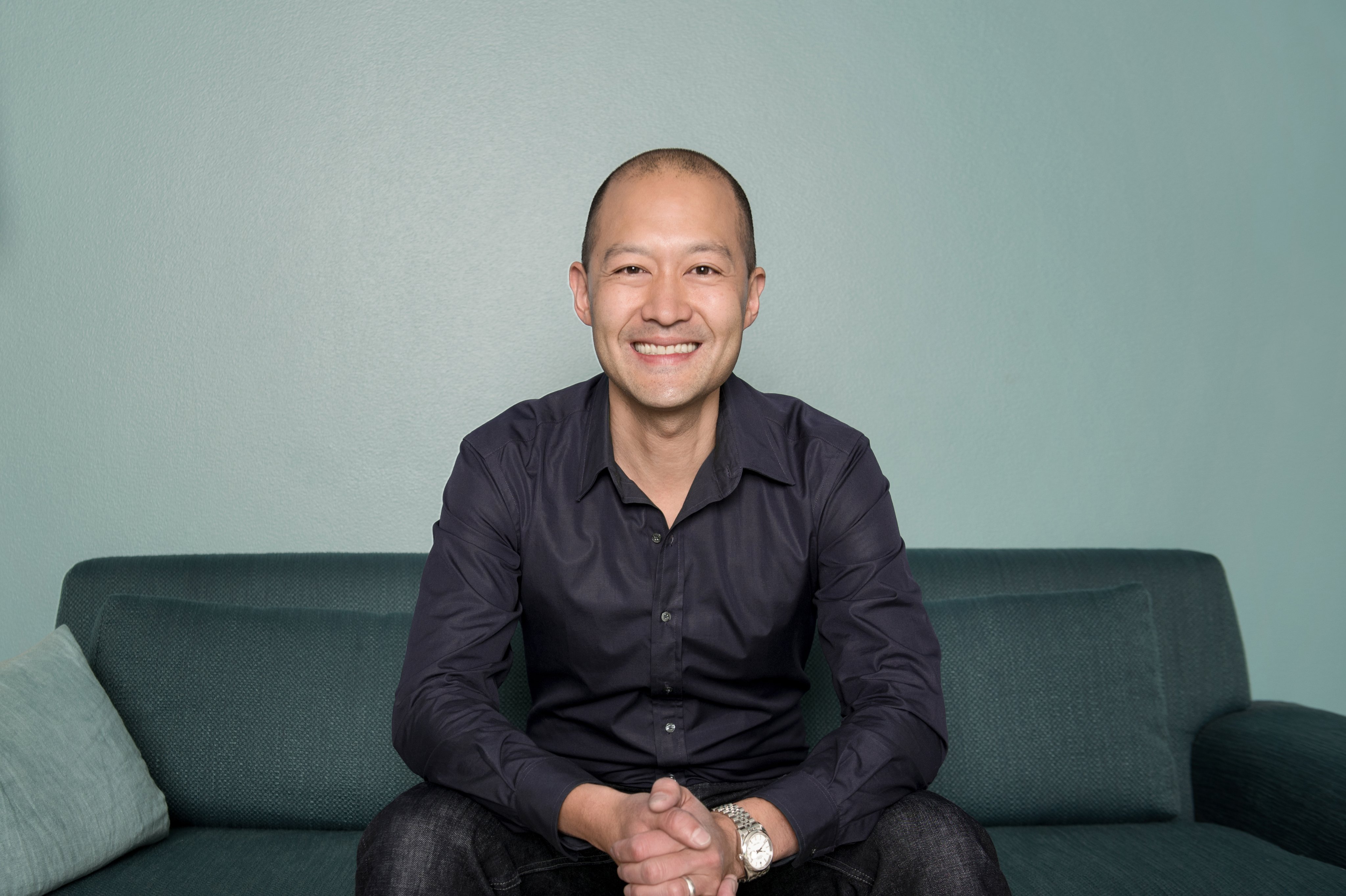 Adyen team member smiling and sitting on a sofa in an office setting