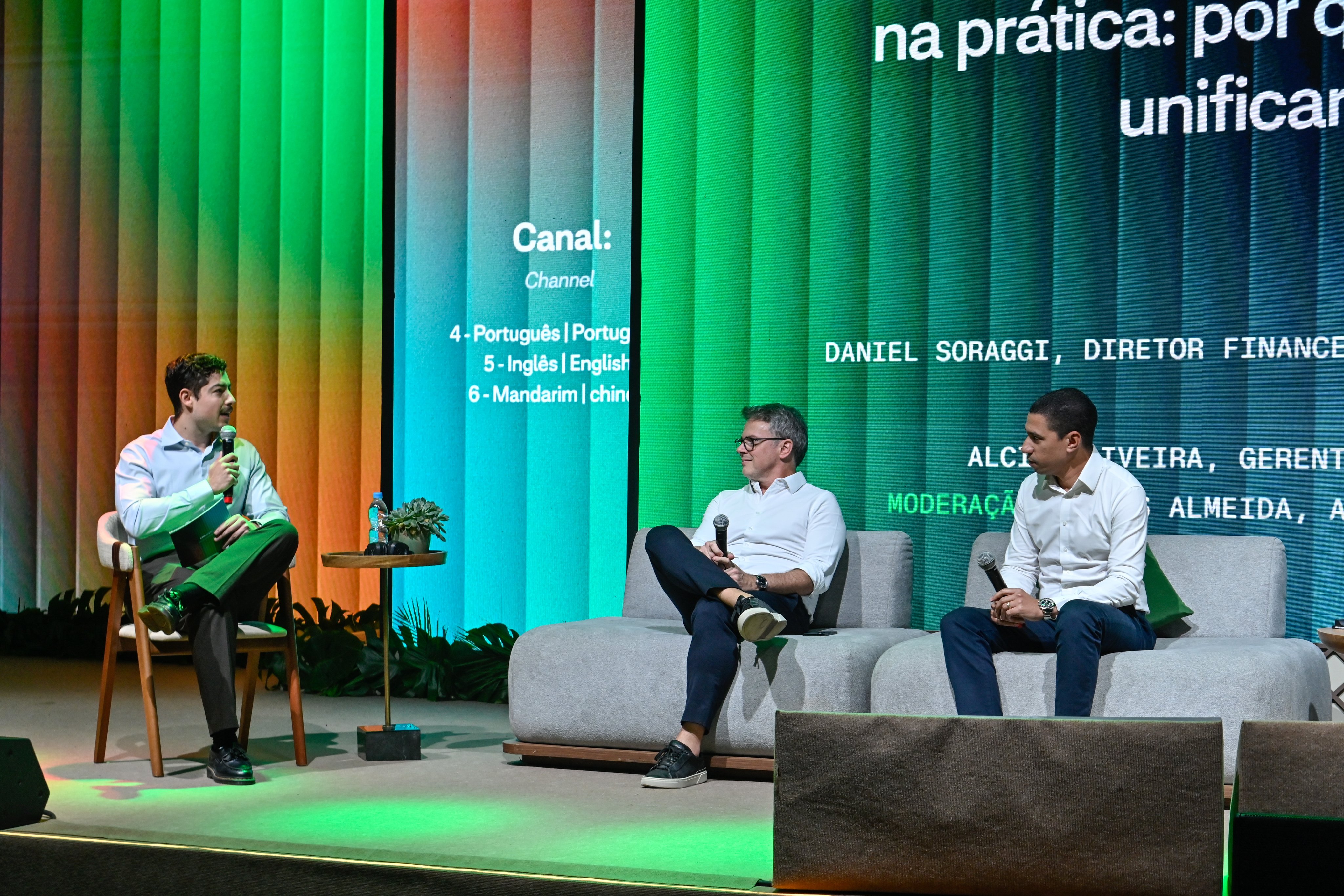 Funcionários da Adyen no escritório da empresa debatem soluções de pagamento no palco, com telão digital ao fundo.