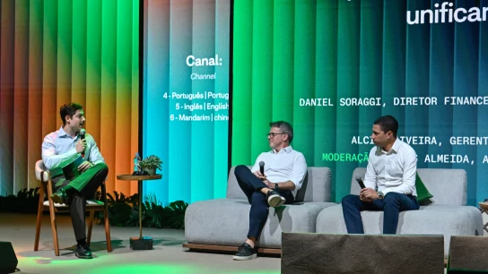 Funcionários da Adyen no escritório da empresa debatem soluções de pagamento no palco, com telão digital ao fundo.