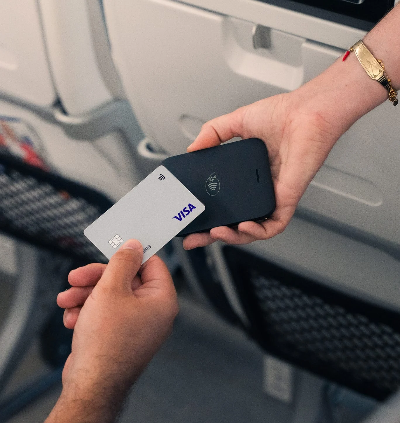 A traveler uses an Adyen card reader to make a contactless payment on a flight.