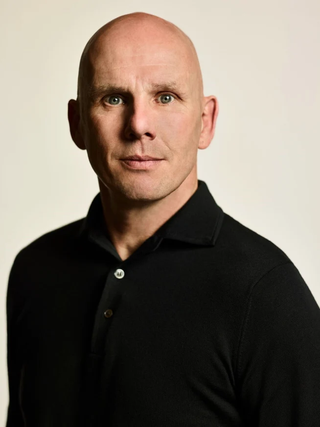 Adyen employee in an office wearing a black shirt, looking directly at the camera.