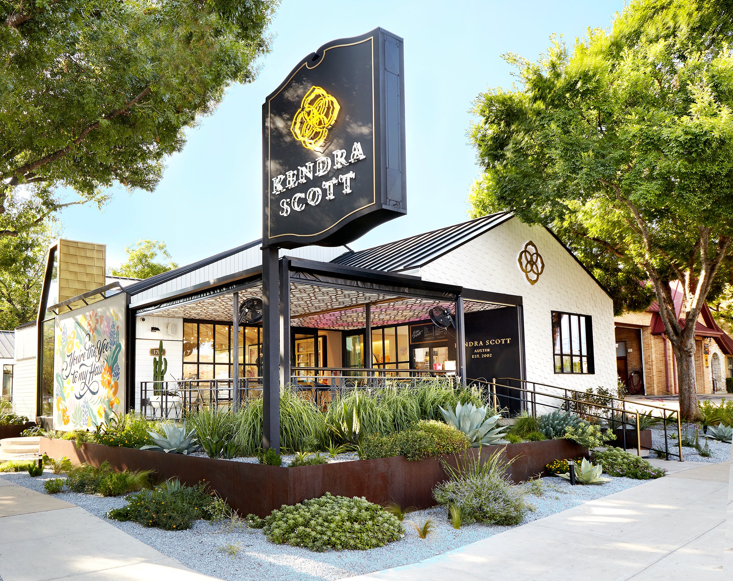Beautiful exterior of Kendra Scott store with greenery and signage.