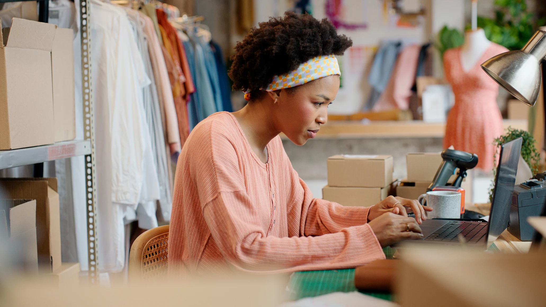 A customer working on a laptop at a workspace with boxes and a payment terminal provided by Adyen.