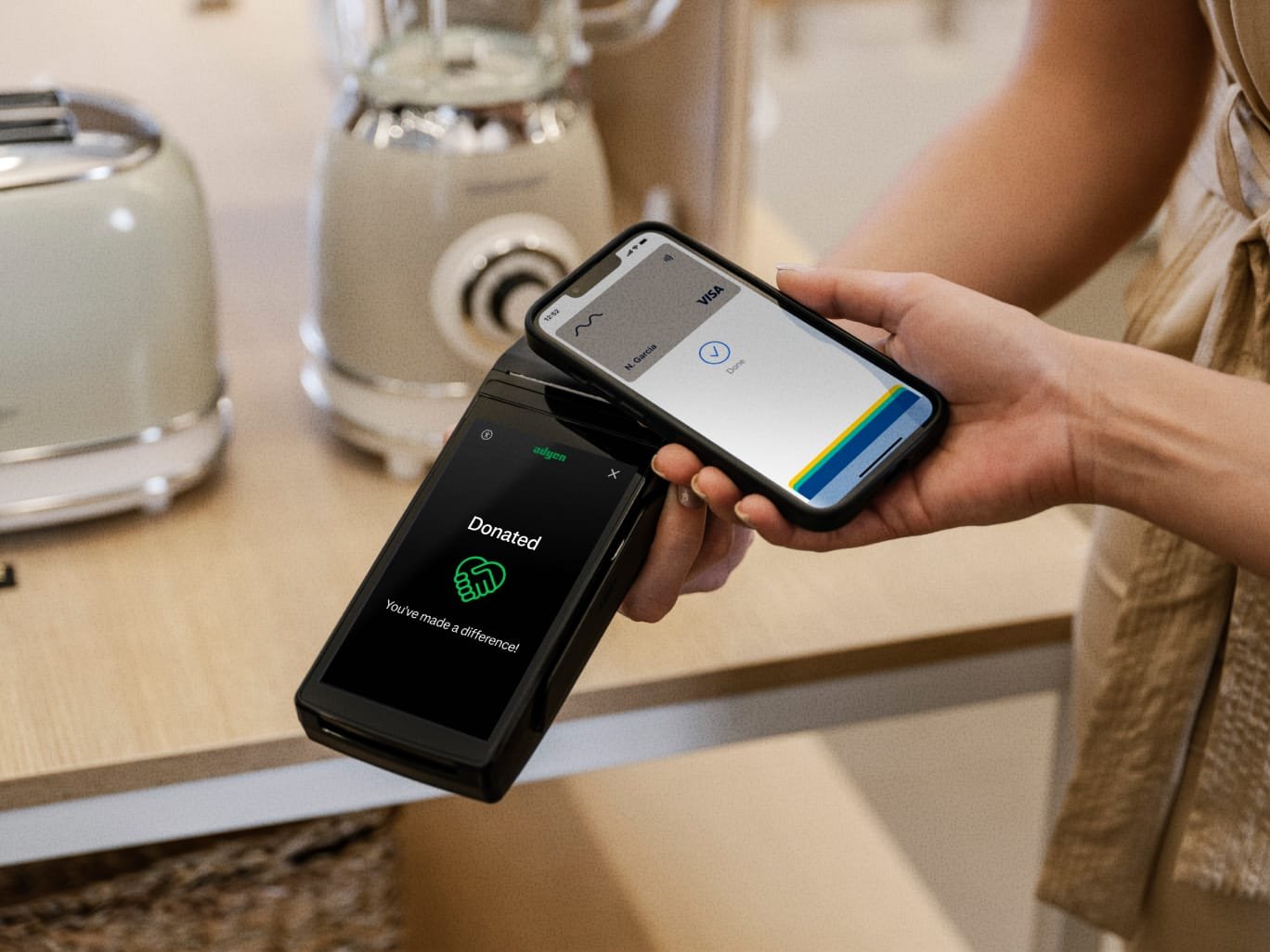 A person making a contactless payment using an Adyen terminal with a smartphone in a business setting.