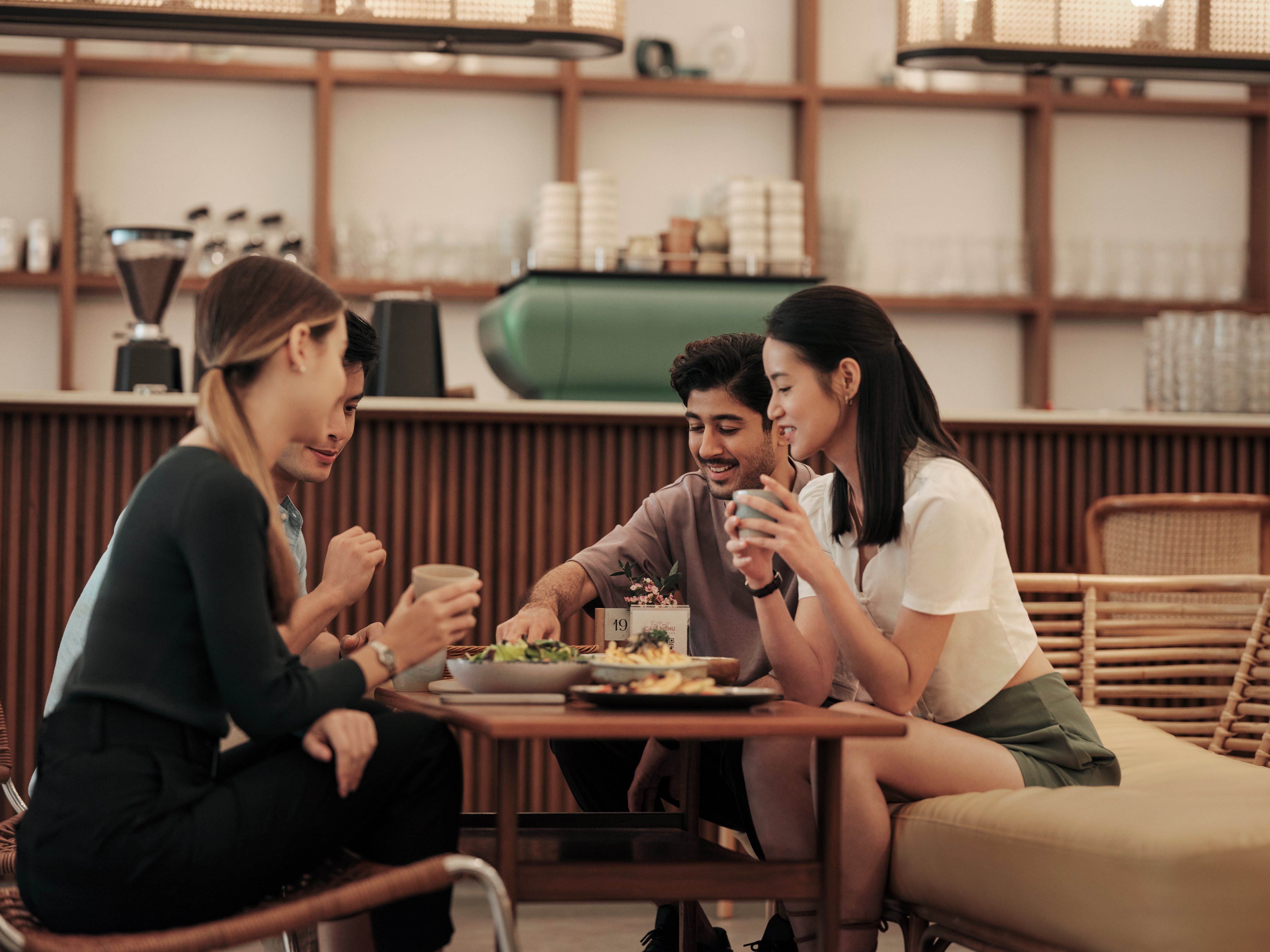 A group of people at a bistro restaurant table, eating and chatting over food.