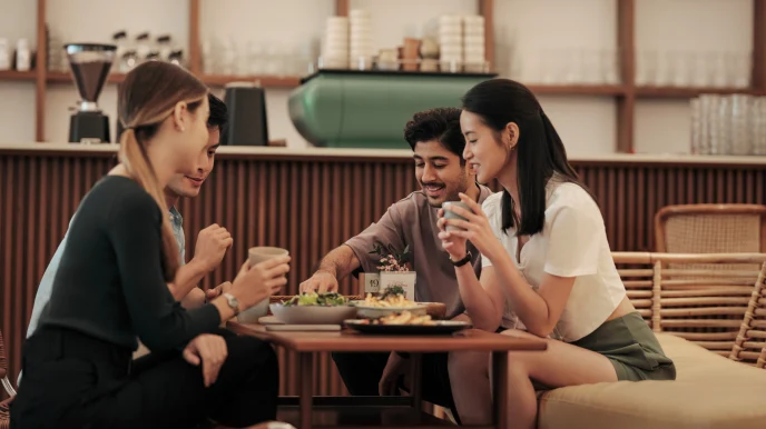 A group of people at a bistro restaurant table, eating and chatting over food.