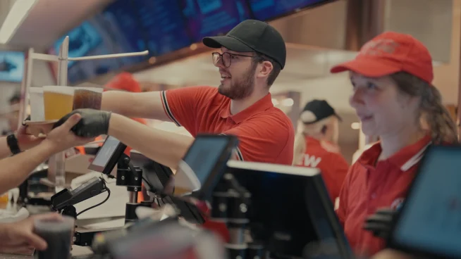 Adyen team members serve customers at a store checkout using an Adyen payment terminal.
