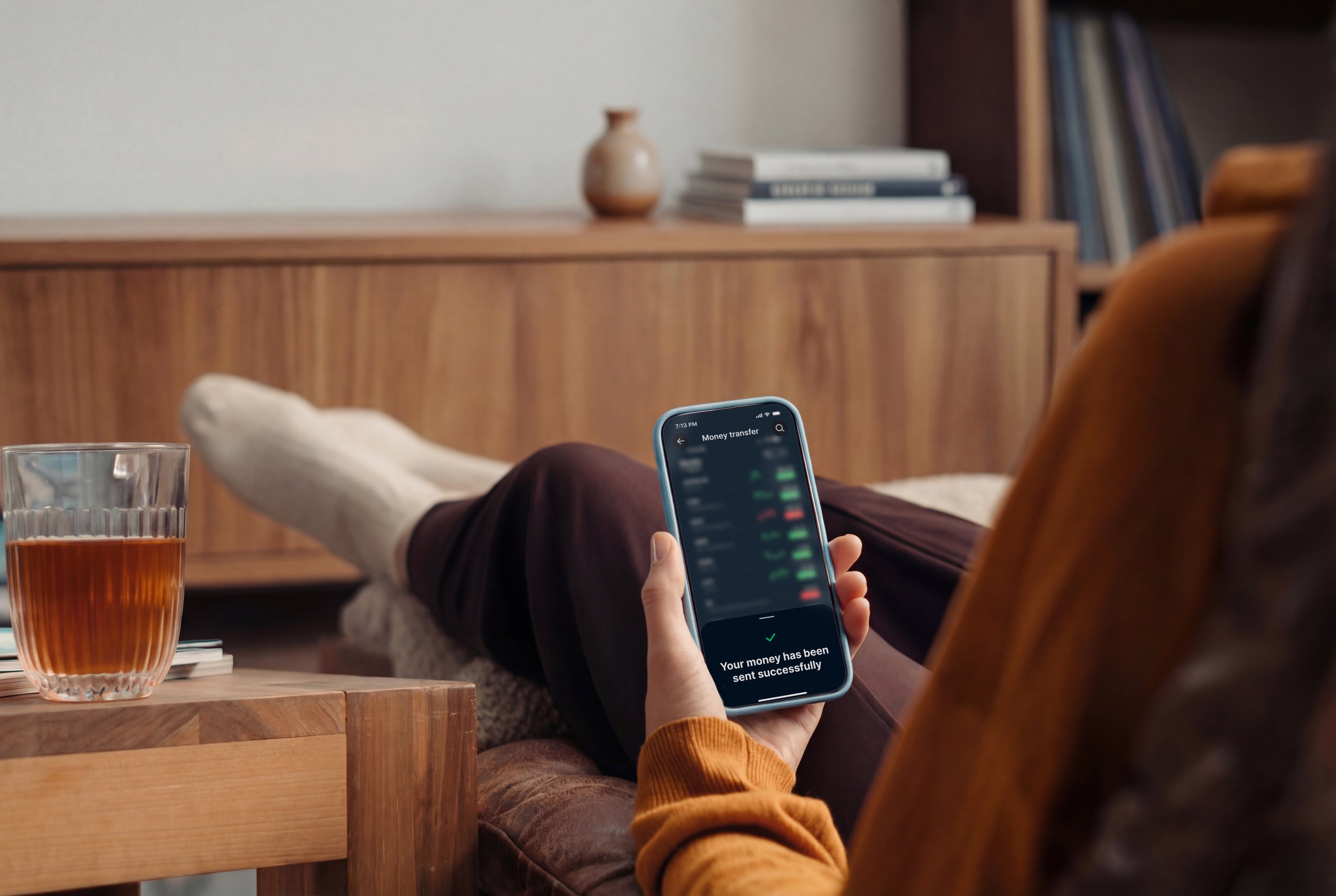 A person using a mobile phone with a payment app at home, supported by Adyen.