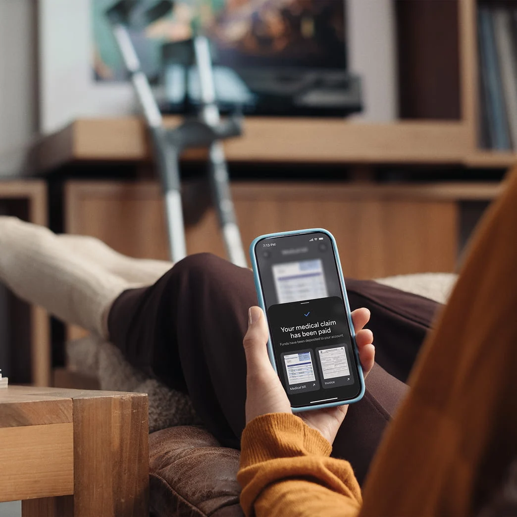 Person using a mobile device to check a medical claim notification at home.