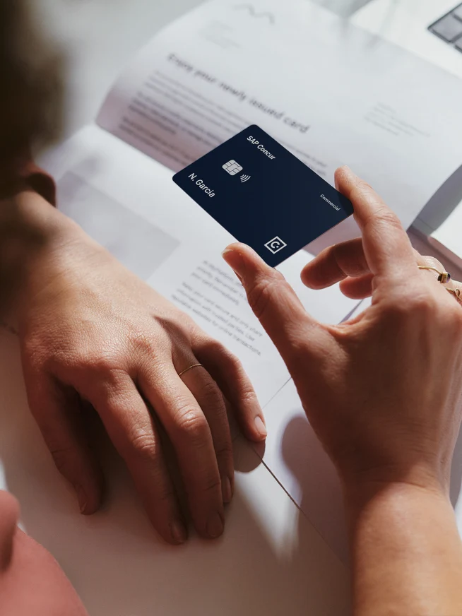 Person using a mobile payment terminal with a laptop and documents on the desk