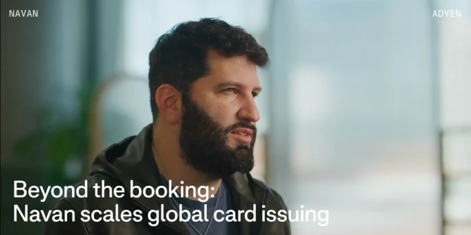 Adyen employee in an office with a screen displaying text about Navan and global card issuing.