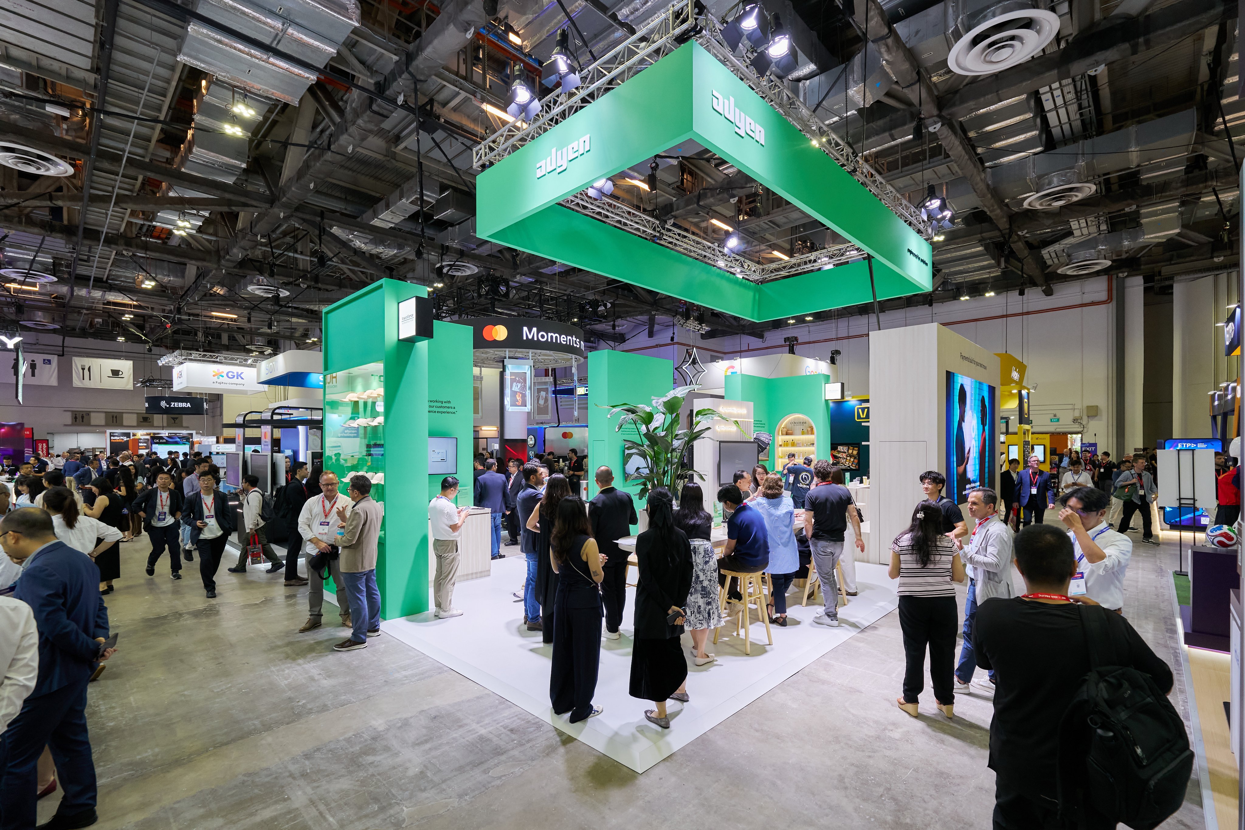 Trade show booth with visitors engaging with Adyen payment solutions at a technology event