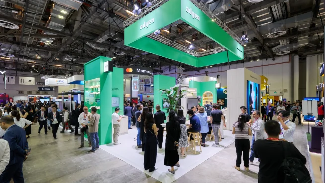 Trade show booth with visitors engaging with Adyen payment solutions at a technology event
