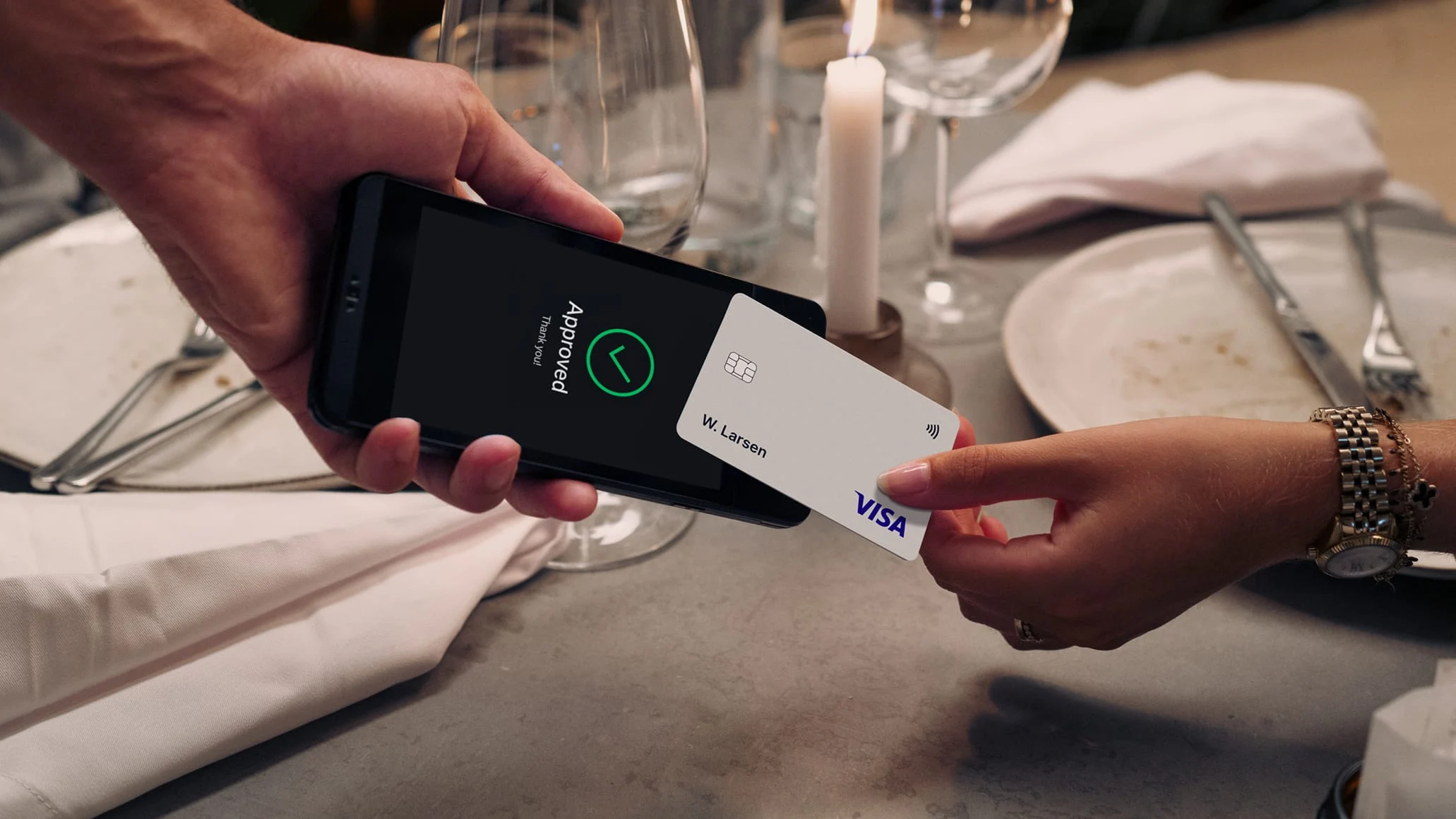 A customer making a contactless payment with an Adyen card terminal at a dining table.