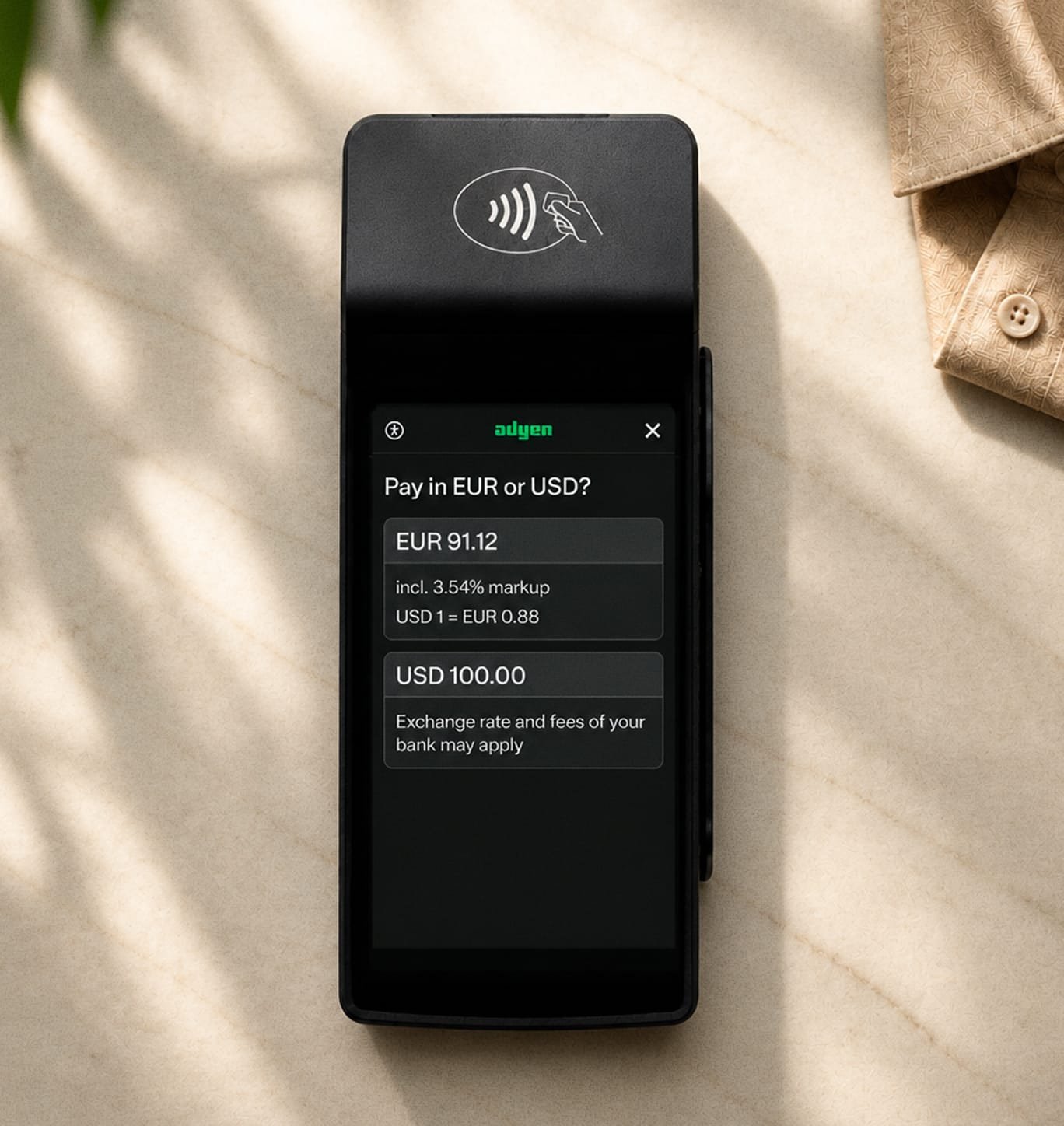 A contactless payment terminal with a screen showing EUR and USD options, provided by Adyen.
