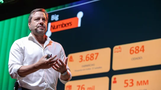 Palestrante em traje formal fala em conferência com tela exibindo estatísticas de pagamentos da Adyen.