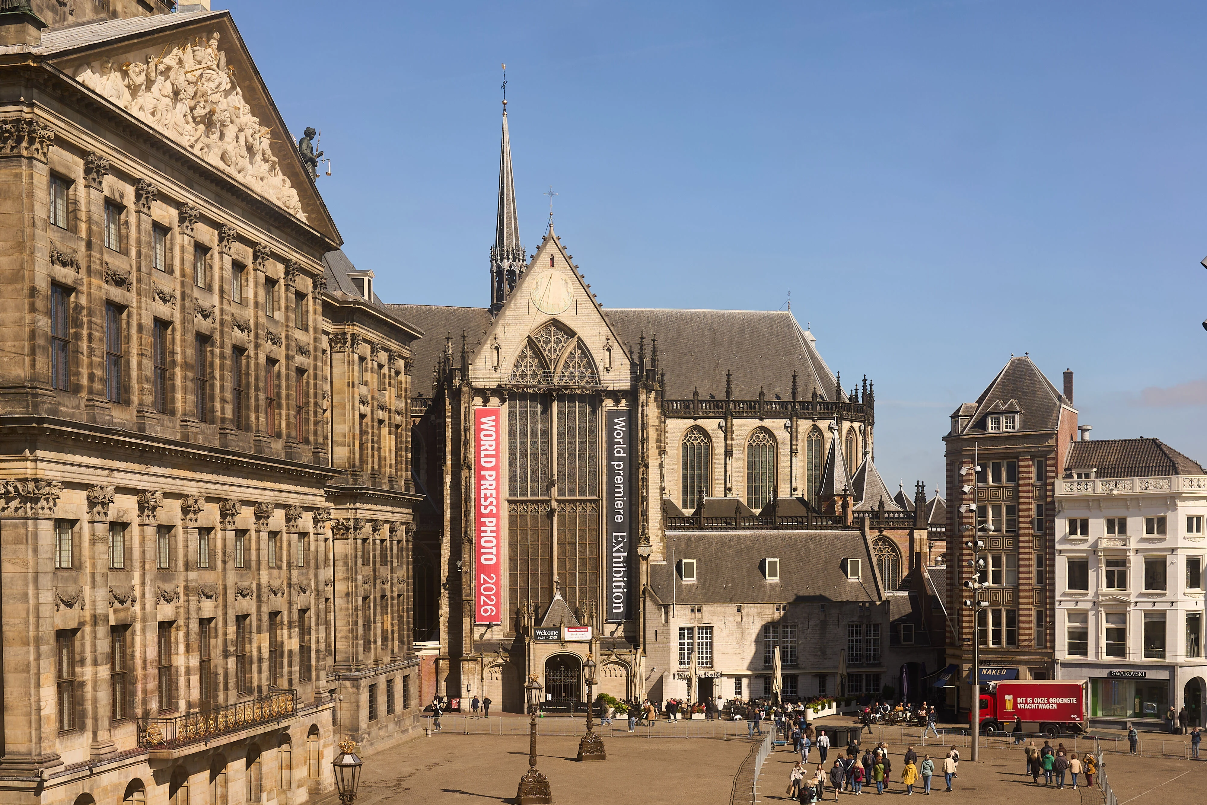 Historic cathedral near an urban square with people and surrounding buildings.