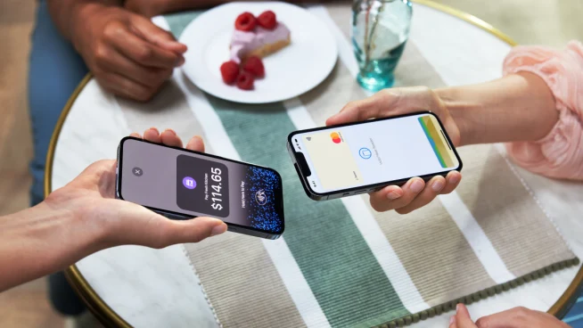 Two individuals making a contactless payment using a smartphone and a portable card reader.