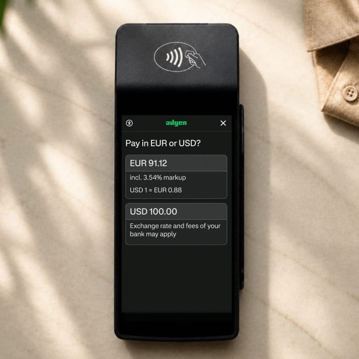 Payment terminal with a screen displaying an EUR or USD payment option, operated by Adyen.