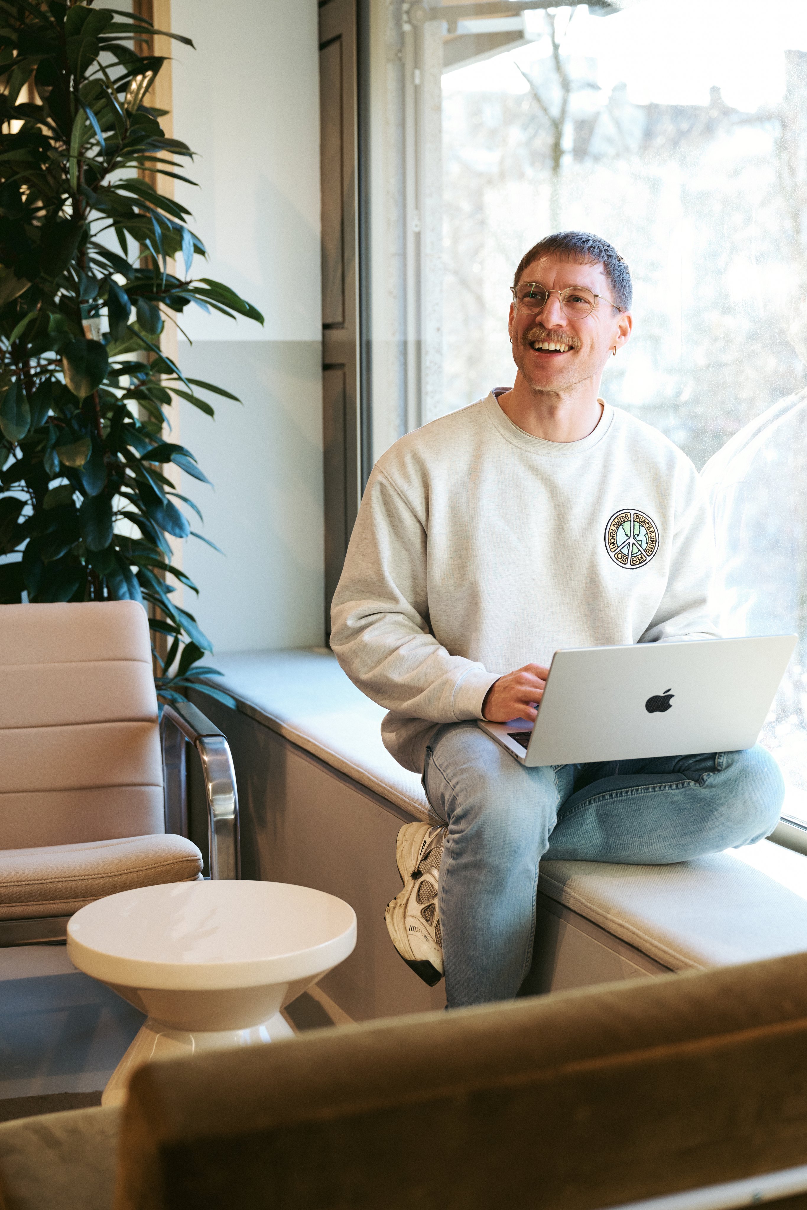 Smiling man in an office environment with laptop on his lap