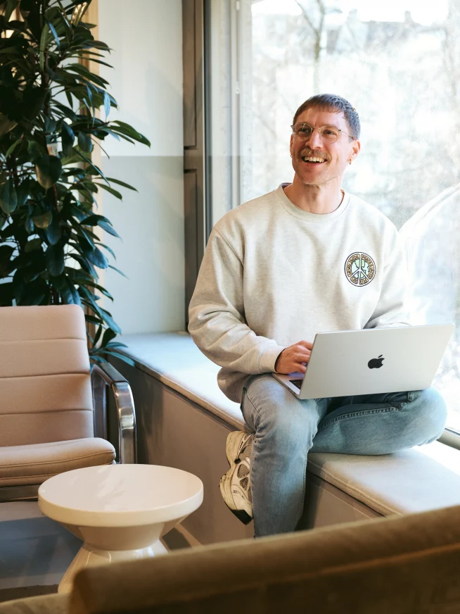 Smiling man in an office environment with laptop on his lap