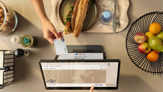 Person paying with a contactless card on an Adyen payment terminal at a restaurant.