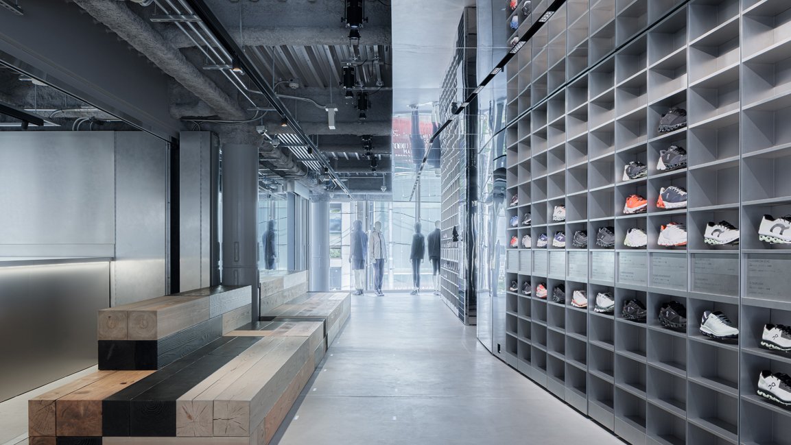 Modern shoe store interior with sneakers displayed on shelves and customers walking.
