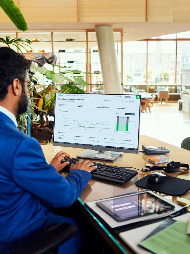 A hotel employee looking at a Adyen dashboard with data charts.