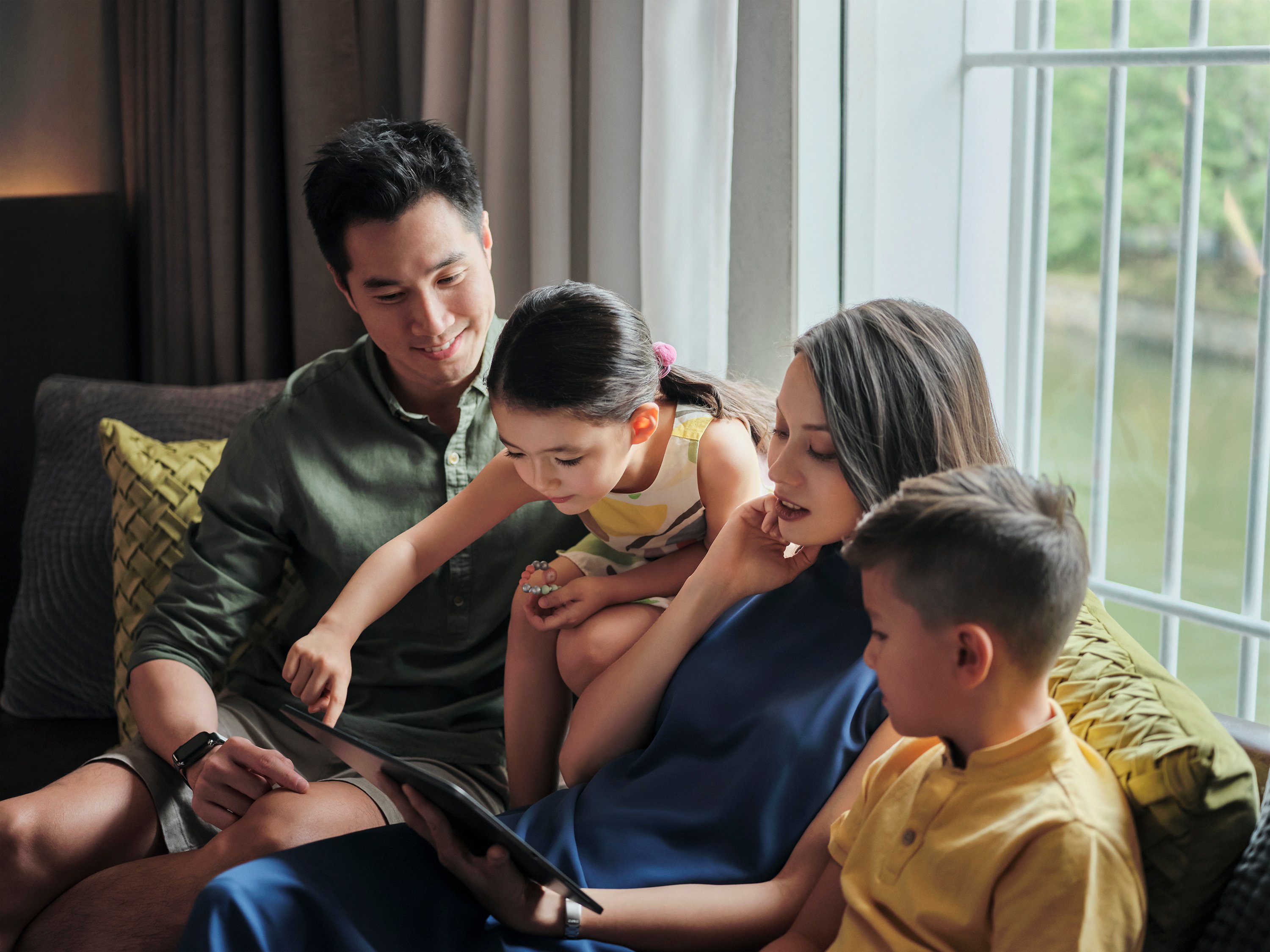 A family with children looking at a tablet in their hotel room.