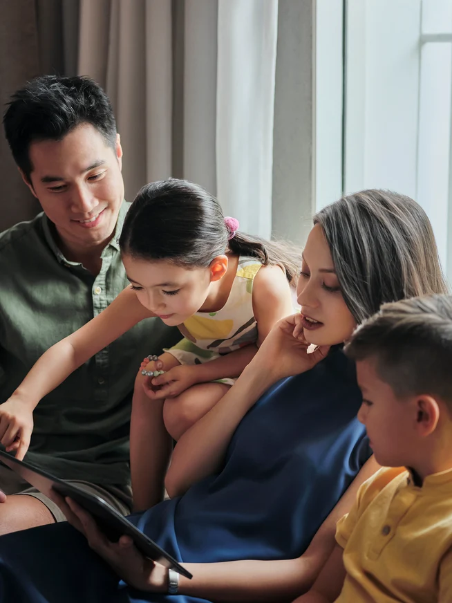 A family with children looking at a tablet in their hotel room.
