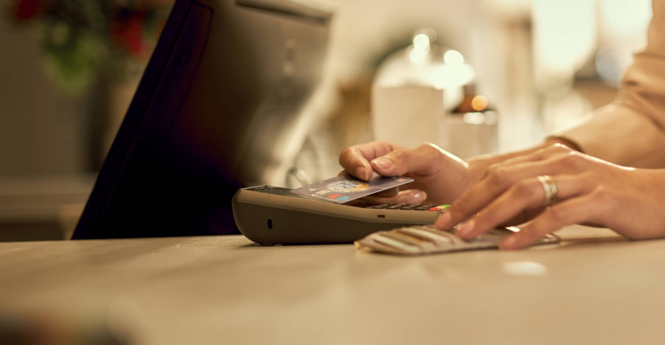 Primer plano de un pago sin contacto en proceso con una tarjeta y un terminal POS.