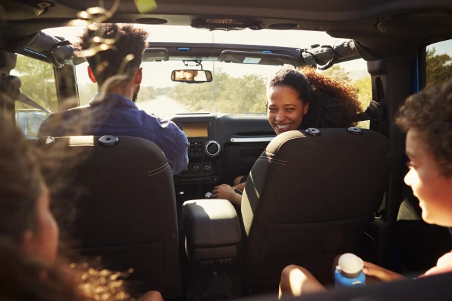 Smiling family sitting inside their car