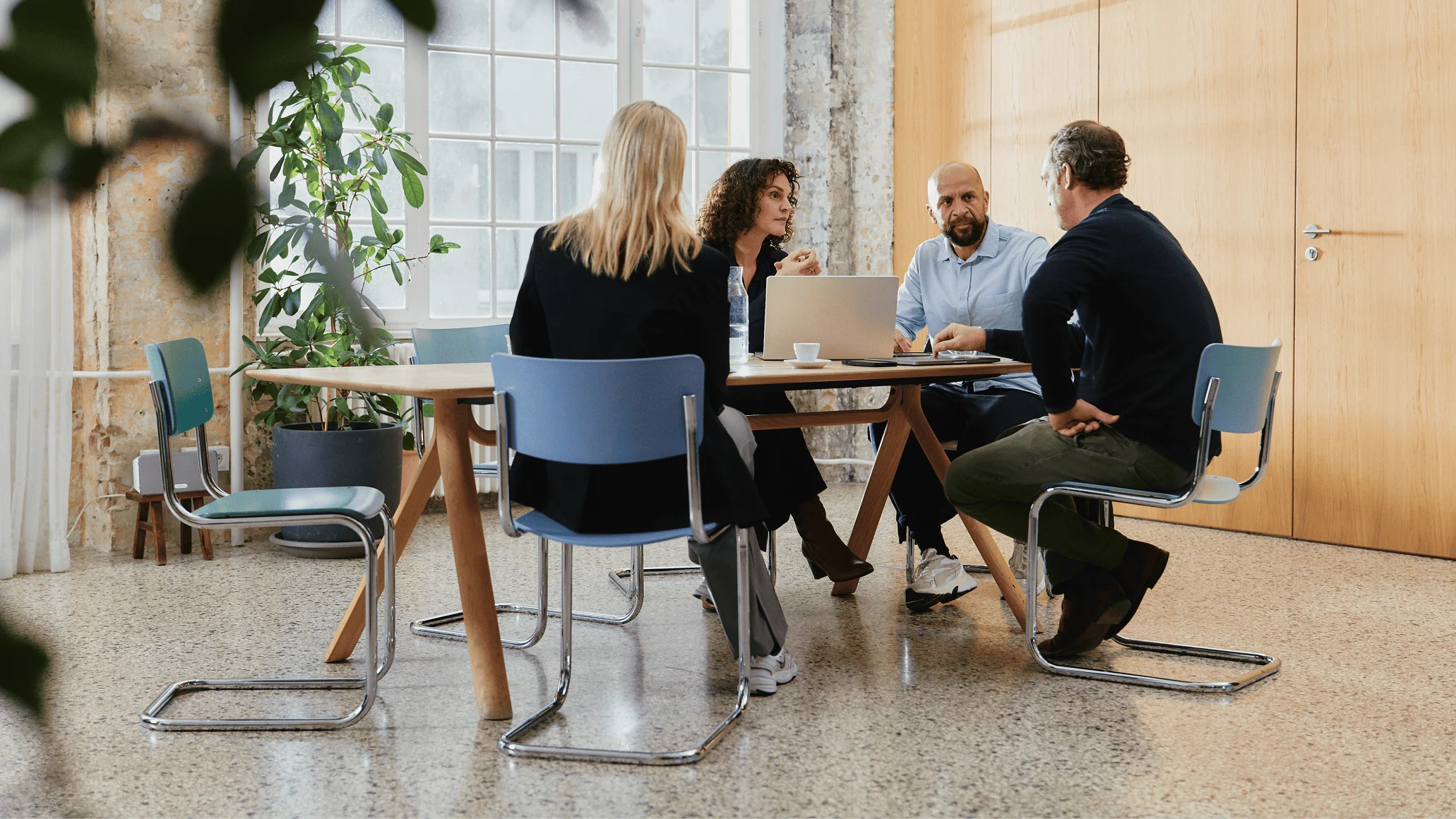 Adyen team members in a meeting at the office, discussing work with laptops and documents.