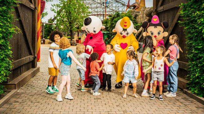 Kinderen bij een ingang met drie mascottes