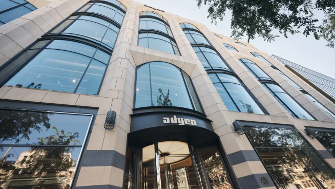 Modern building exterior with large glass windows and the Adyen logo above the entrance.