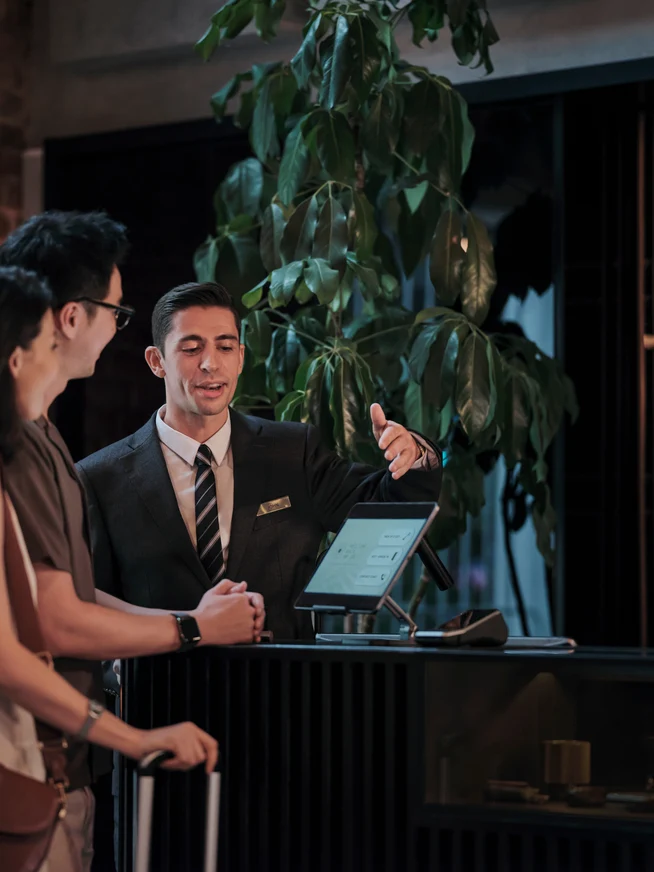 A couple checking into a hotel room at reception desk.
