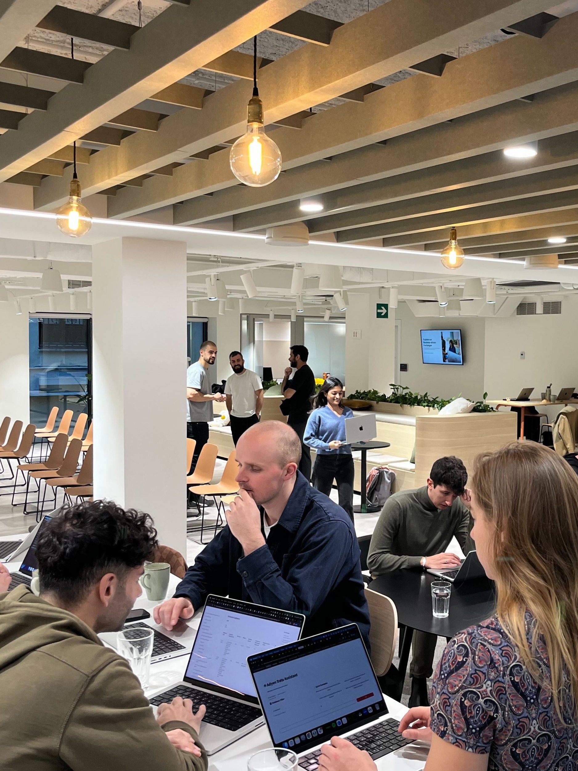 Adyen employees in the office collaborating at a meeting with laptops and discussion