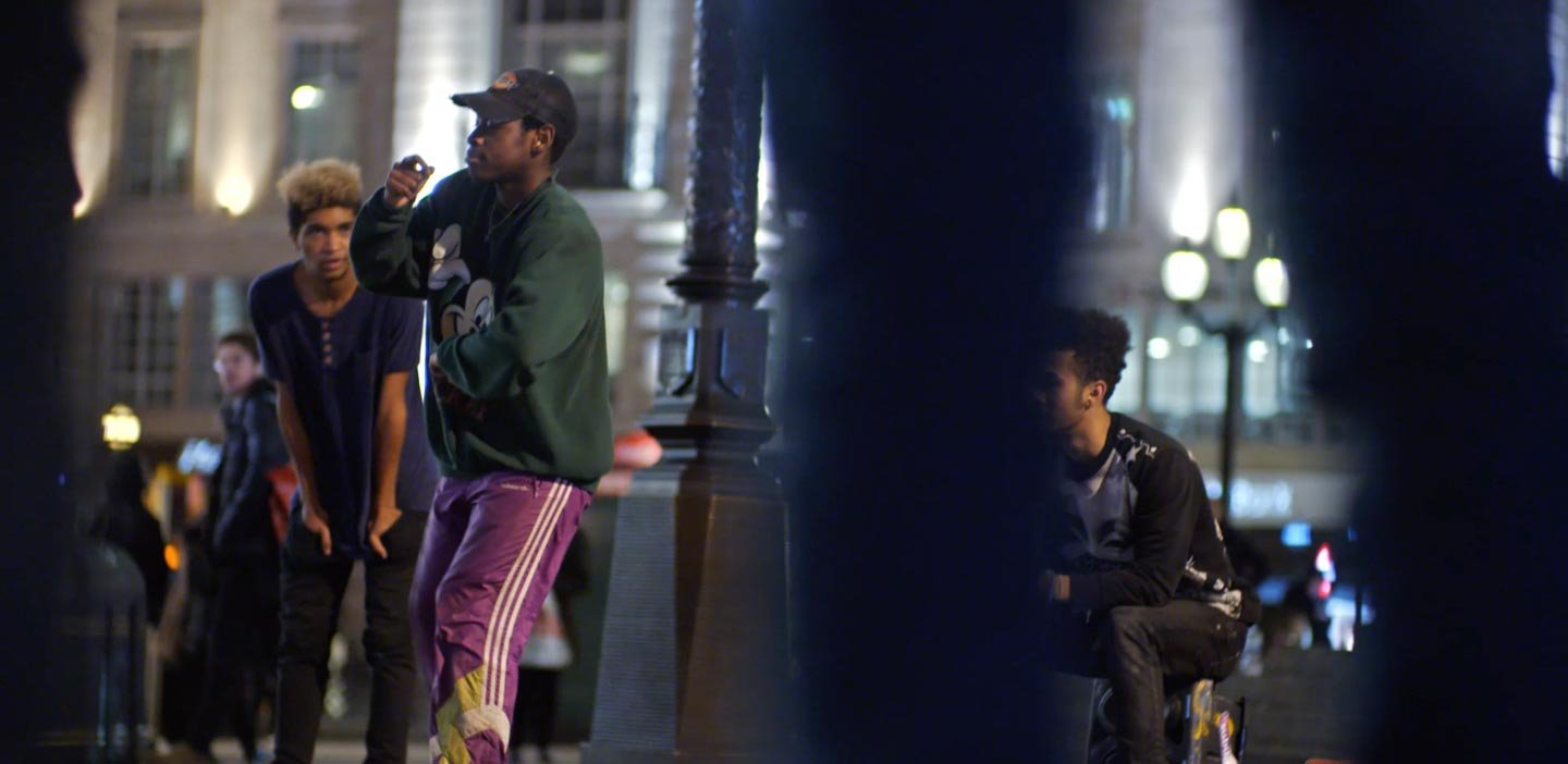 Grupo de jóvenes adultos reunidos en una calle de la ciudad por la noche.