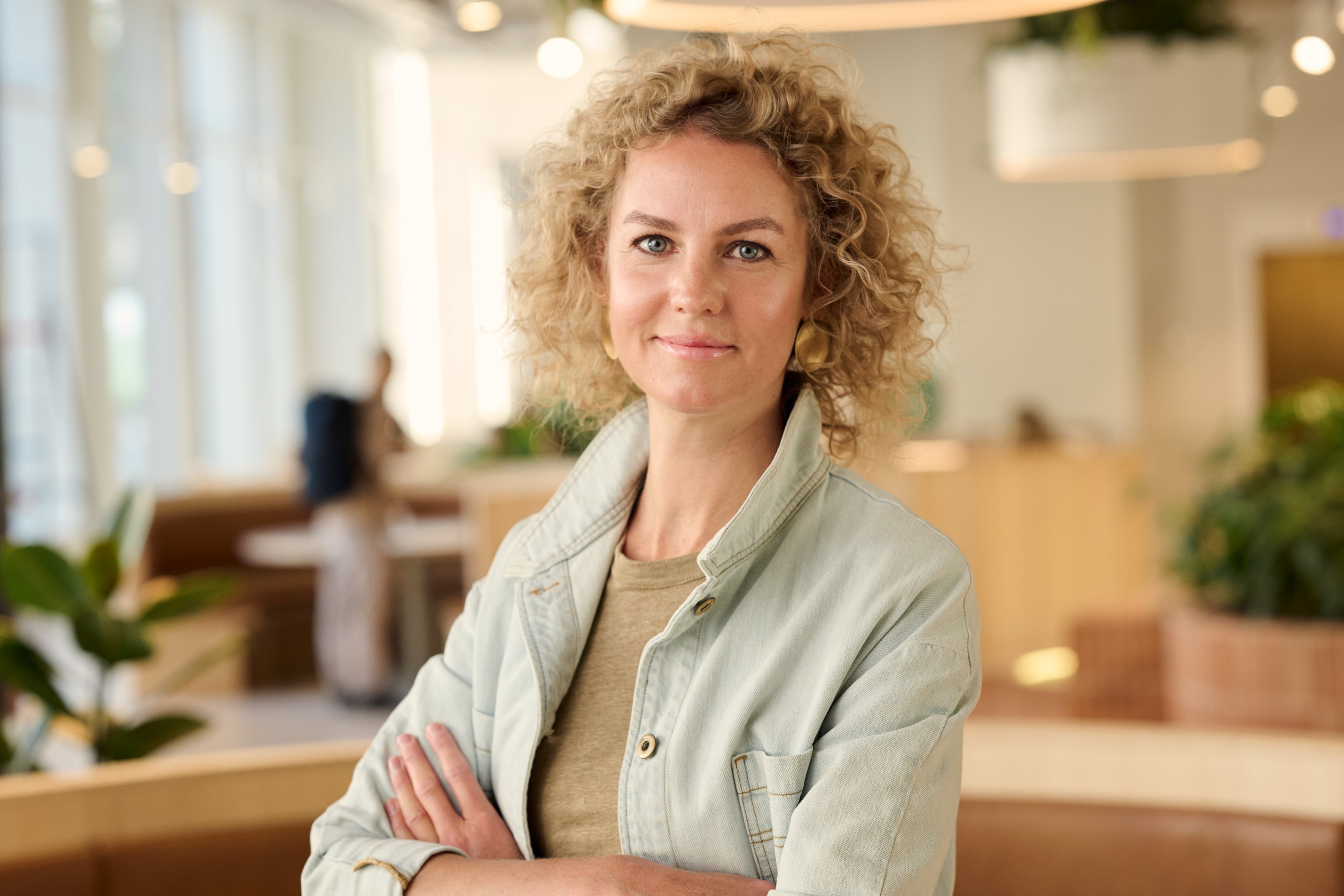 Adyen team member standing confidently in a modern office environment with plants and natural light.