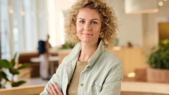 Adyen team member standing confidently in a modern office environment with plants and natural light.