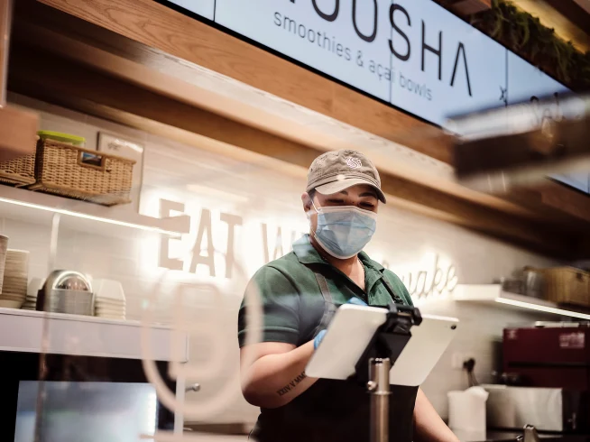 A customer service representative using an Adyen terminal at a smoothie shop.