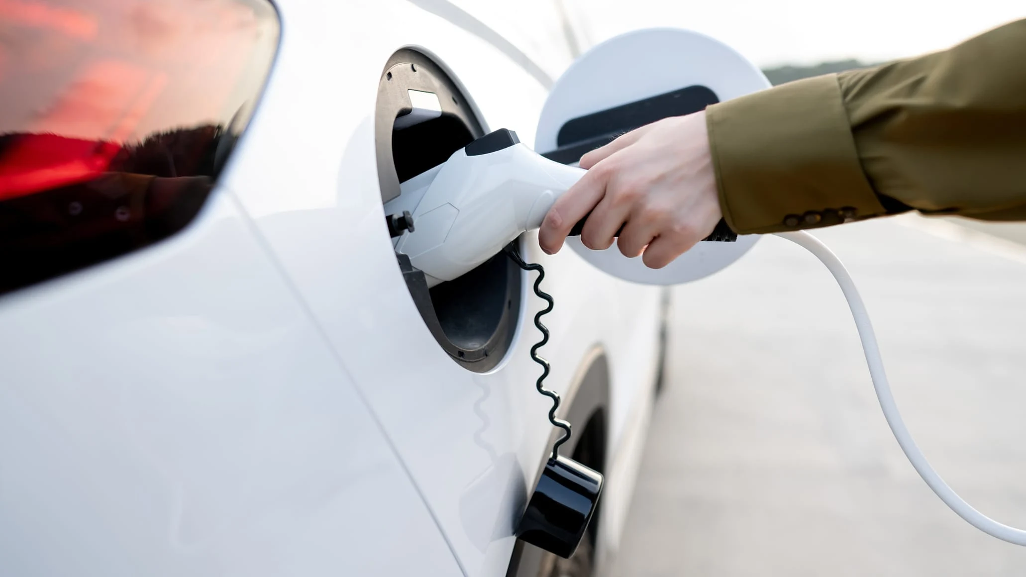 A person charges an electric vehicle using a charging station.