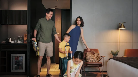 Una familia con hijos instalándose en su habitación de hotel después de registrarse en la recepción del hotel.