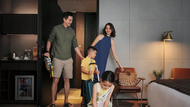 Una familia con hijos instalándose en su habitación de hotel después de registrarse en la recepción del hotel.