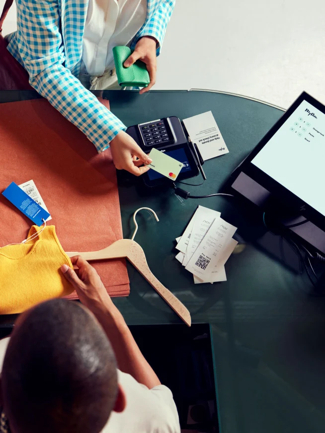 A woman in a clothing store paying by tapping her card on Adyen's M400 terminal.