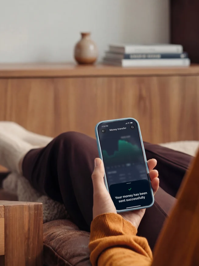 A person relaxing at home using a smartphone with a visible screen, enjoying a drink