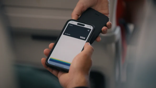 Traveler using a smartphone with an Adyen mobile payment app at an airport terminal