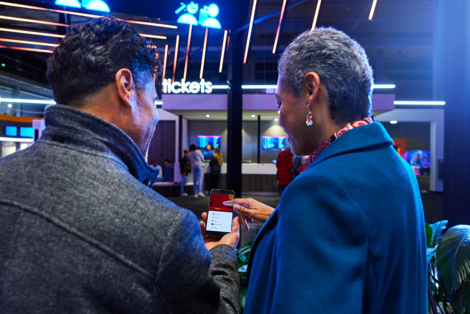 Cinema guests buying tickets to the movies on a smartphone.