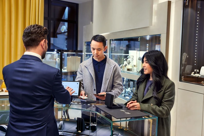 A couple at a jewelry store counter paying for earrings by tapping their card on Adyen's P400 terminal.