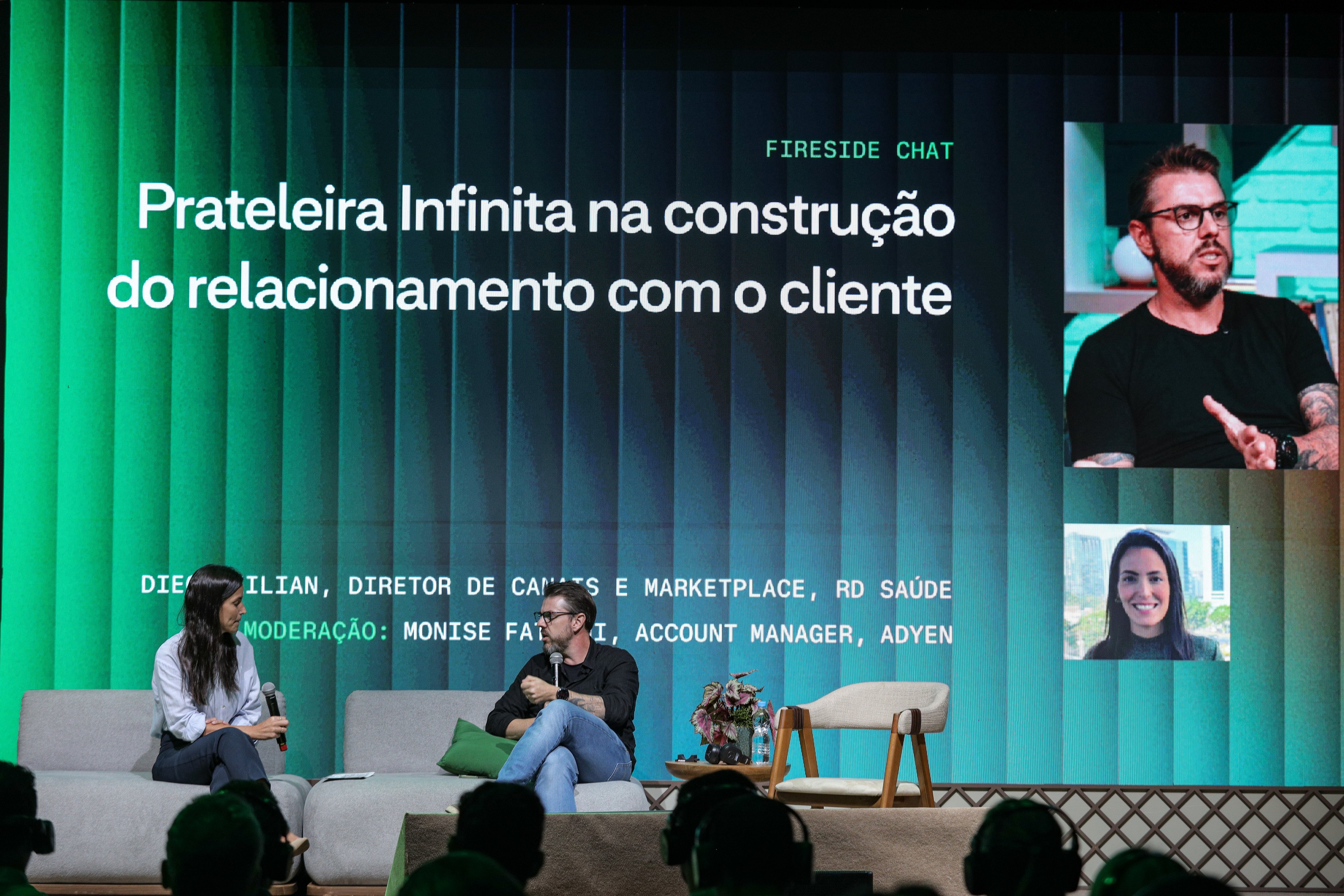 Membros da equipe da Adyen conversam durante evento corporativo com tela de apresentação ao fundo.